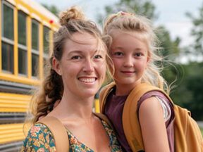 A mom and a grade-school daughter by a school bus