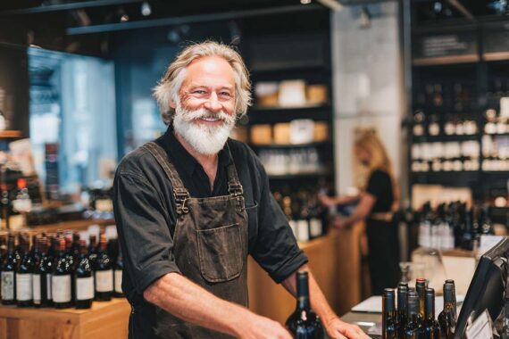 Image of a male merchant wiht a beard in his wine shop