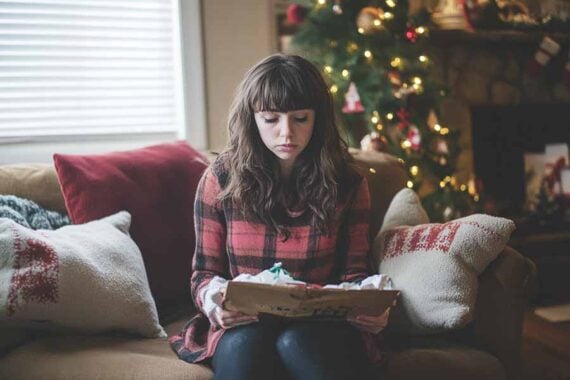 Photo of a teenage female looking sad in front of a Christmas tree Photo of a teenage female looking sad in front of a Christmas tree