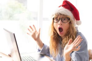 business woman in office with computer and santa claus hat surprised