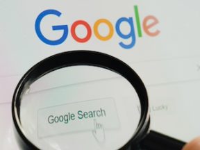 Google logo behind a magnifying glass