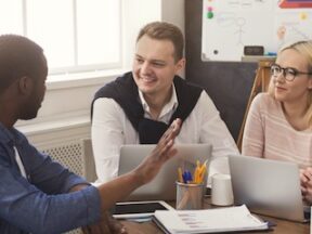 Image of a 3-person marketing team at a table with computers and charts