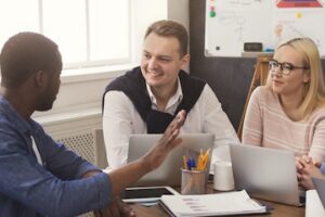 Image of a 3-person marketing team at a table with computers and charts