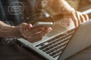 Photo of a hands on a keyboard while holding a smartphone