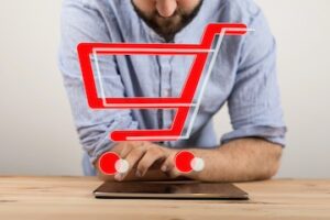 Image of male looking at a tablet computer with a shopping cart icon on top
