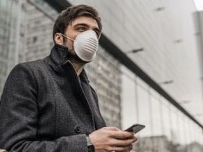 Man wearing a mask holding a smartphone