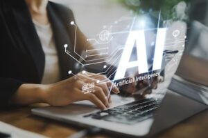 Image of a person typing on a laptop with the illustration "AI" superimposed
