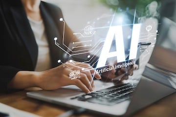 Image of a person typing on a laptop with the illustration "AI" superimposed