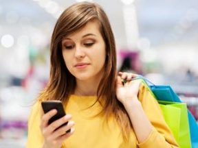 Photo of a female shopper using a mobile phone in a physical store