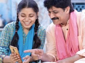 Photo of an Indian man and teenage daughter looking at a smartphone