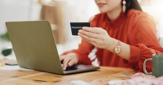 Female holding a credit card in front of a laptop. Female holding a credit card in front of a laptop.