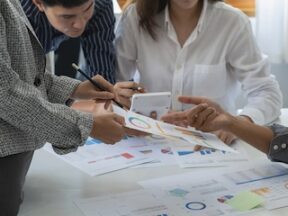 Image of three people at a table looking at charts