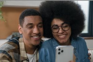 Image of a male and female influencers talking into a smartphone