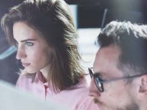 Photo of a female and male in front of a computer in a work environment