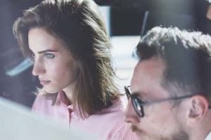 Photo of a female and male in front of a computer in a work environment