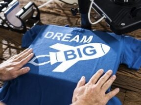 Image of a t-shirt being printed with the words "Dream Big"