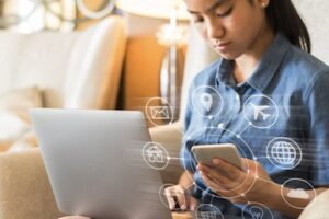 Female looking at a laptop and a smartphone