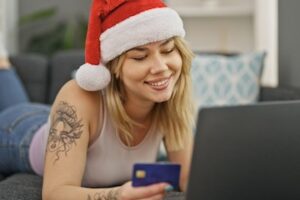 Photo of a 20s-aged female in front of a laptop wearing a Santa cap